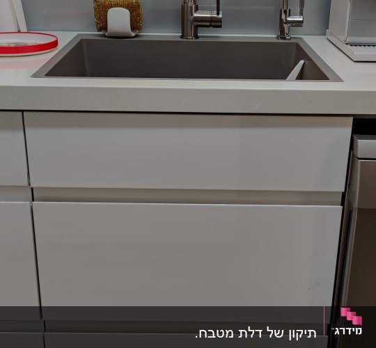 כיור מטבח עם ברזים מודרניים וספוג לניקוי